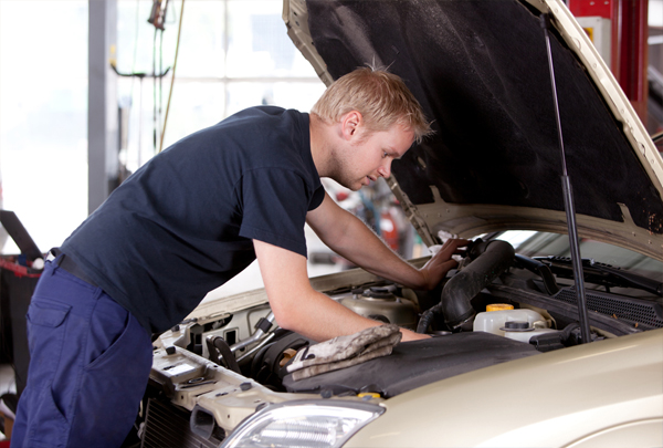 car mechanic looking under hood of car